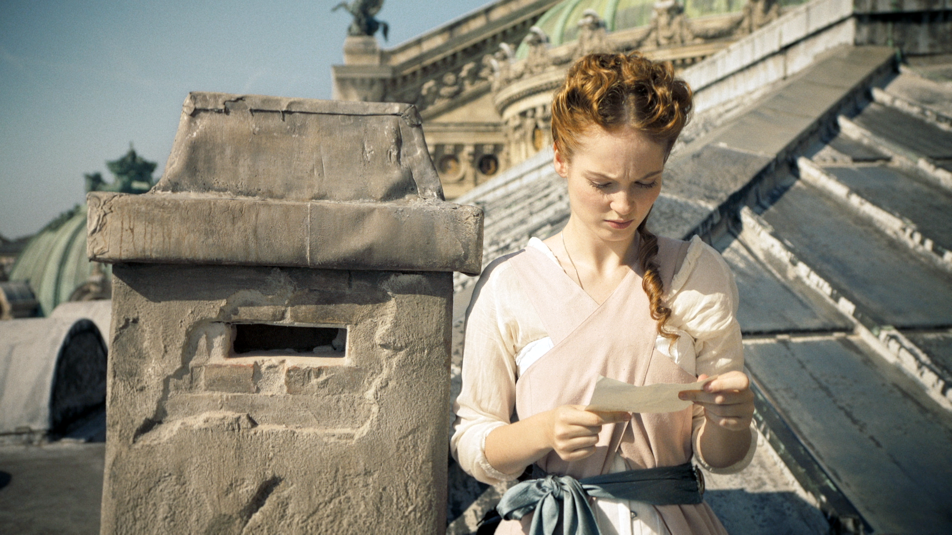 Thea steht auf dem Dach der Pariser Oper. Sie liest einen Brief, den sie in den Händen hält.