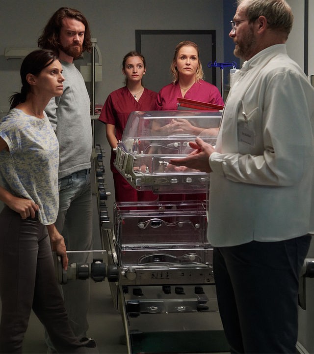 Dr. Keller (Thomas Limpinsel, r.) teilt den entsetzten Eltern Nadia (Leni Adams, l.) und Felix Berger (Sebastian Fräsdorf, 2.v.l.) mit, dass ihr Baby umgehend operiert werden muss. Auch Hebamme Lena Lorenz (Judith Hoersch, 2.v.r.) und Praktikantin Celine Gollert (Paulina Rümmelein, M.) sind schockiert über die schlechte Nachricht.