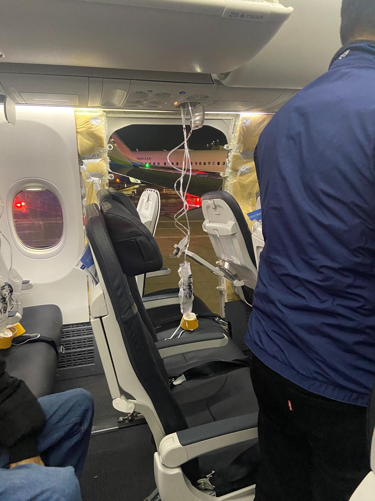 Sauerstoffmasken für Passagiere hängen vom Dach neben einem fehlenden Fenster und einem Teil einer Seitenwand eines Alaska-Airlines-Fluges 