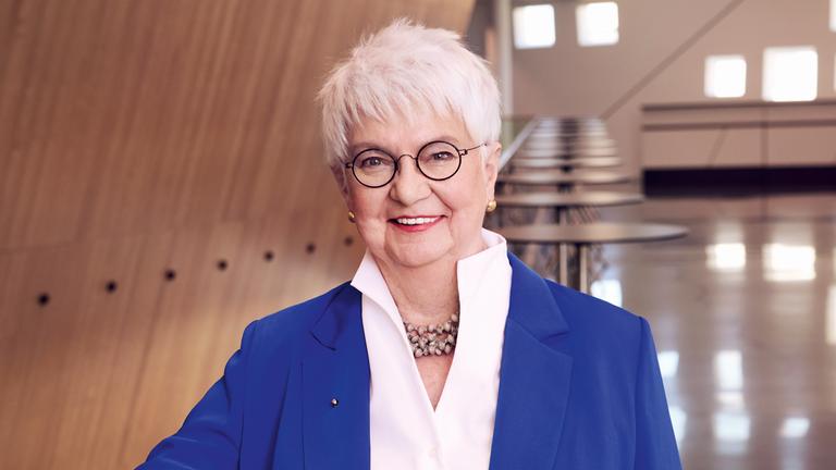 Gerda Hasselfeldt blickt freundlich in die Kamera. Die ZDF-Fernsehratsvorsitzende steht vor moderner Architektur und wirkt präsent und nahbar
