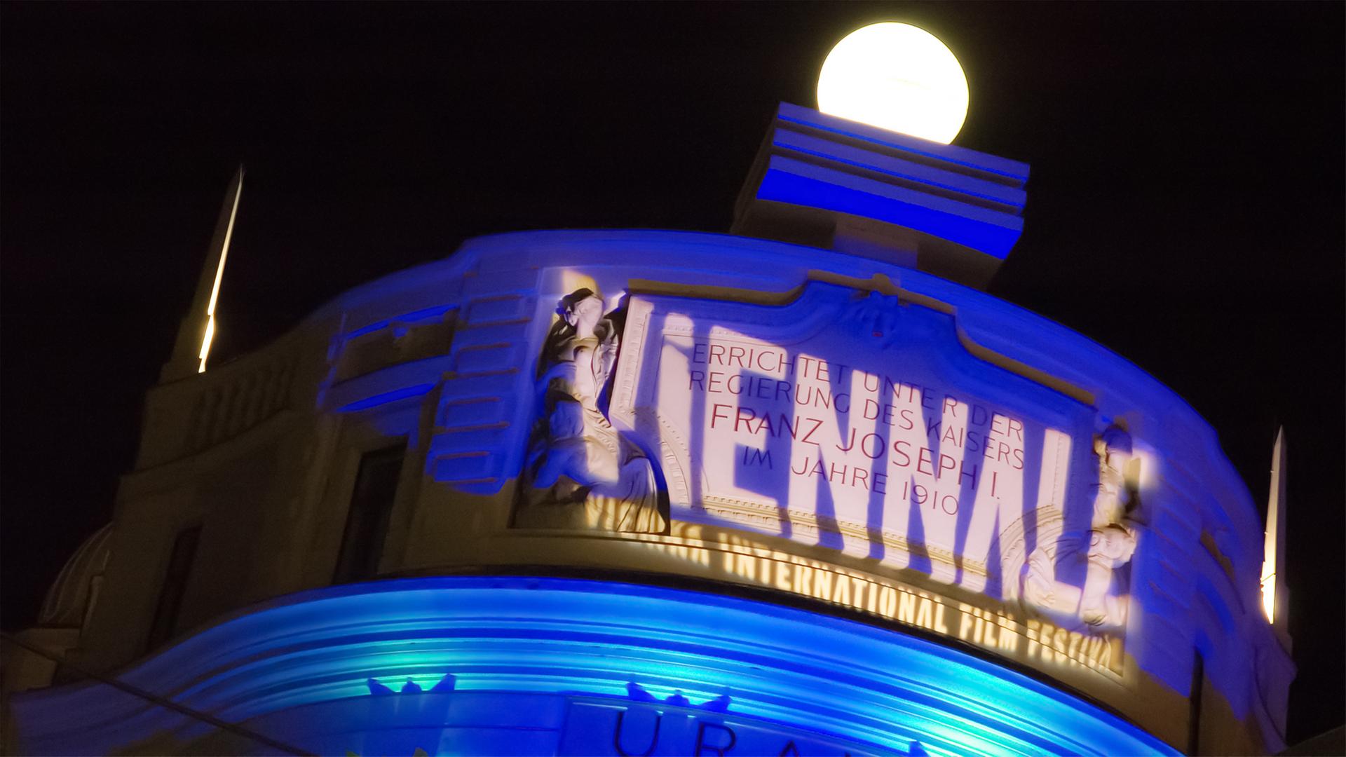 Ein historisches Gebäude wird im Dunkeln von dem Schriftzug "Viennale" angestrahlt.