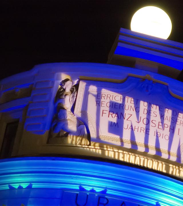 Ein historisches Gebäude wird im Dunkeln von dem Schriftzug "Viennale" angestrahlt.
