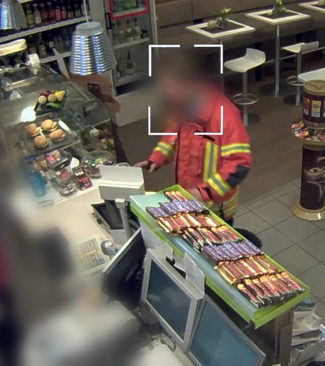 Bild aus einer Überwachungskamera: Verkaufsraum einer Tankstelle von der Kasse aus fotografiert. Ein Feuerwehrmann bezahlt etwas an der Kasse. Sein Gesicht wurde technisch verfremdet. Links daneben: Lichtschematische Darstellung eines Fingerabdrucks.