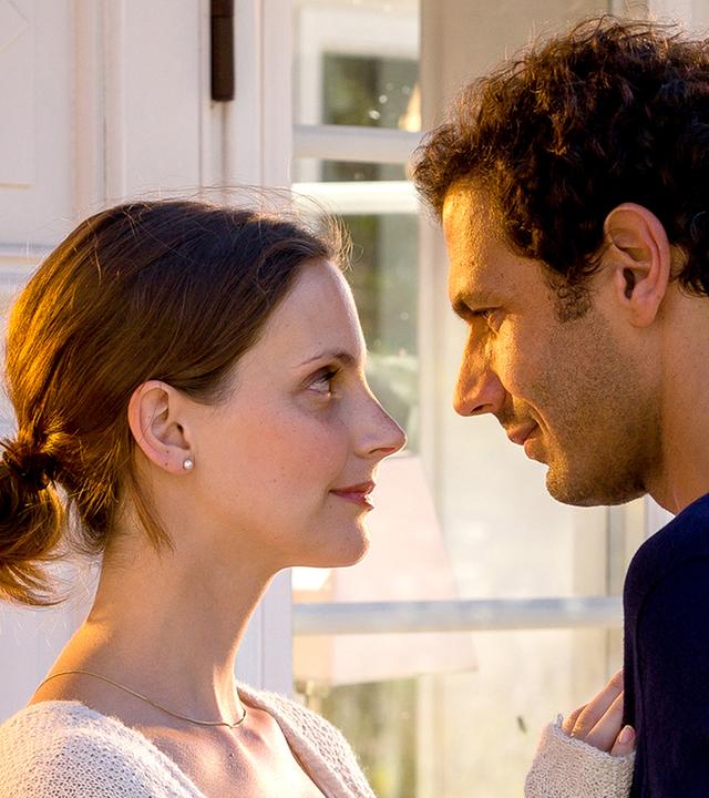 Paul (Mehdi Nebbou) und Sofia (Marie Zielcke) stehen vor einem Fenster und schauen sich tief in die Augen.