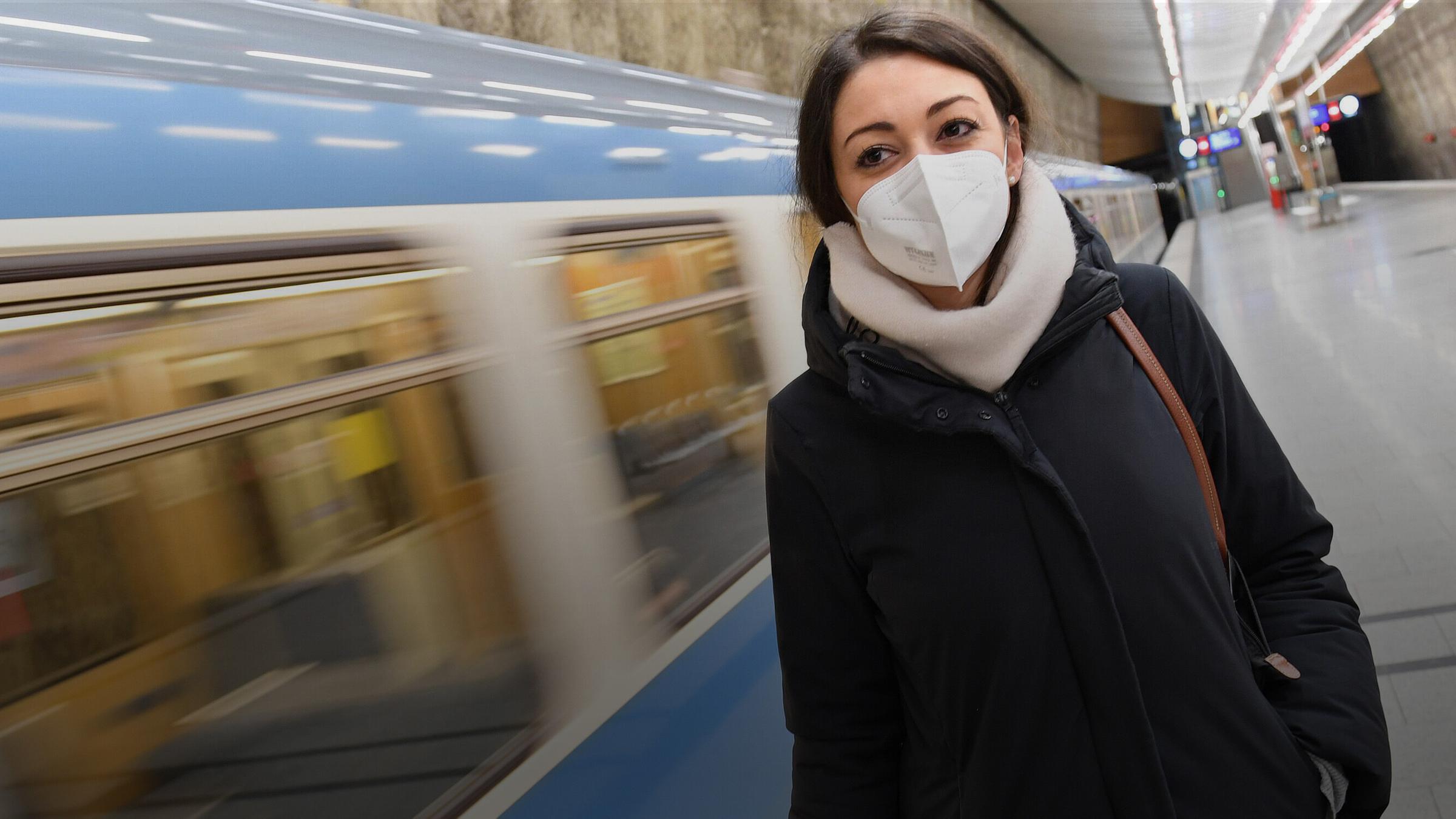 Eine junge Frau mit FFP2-Mundschutz steht vor einem einfahrenden Zug in München am 15.01.2021