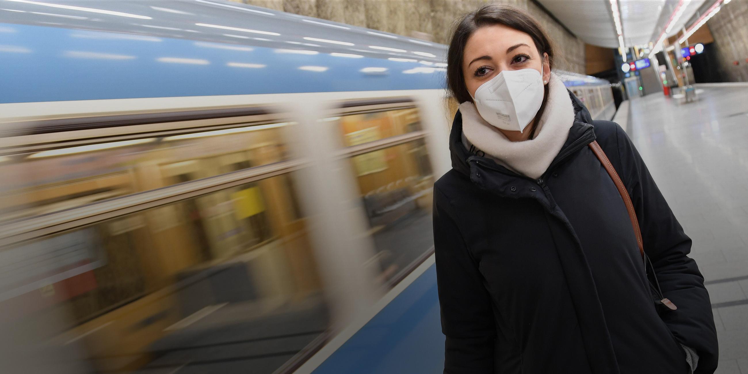 Eine junge Frau mit FFP2-Mundschutz steht vor einem einfahrenden Zug in München am 15.01.2021