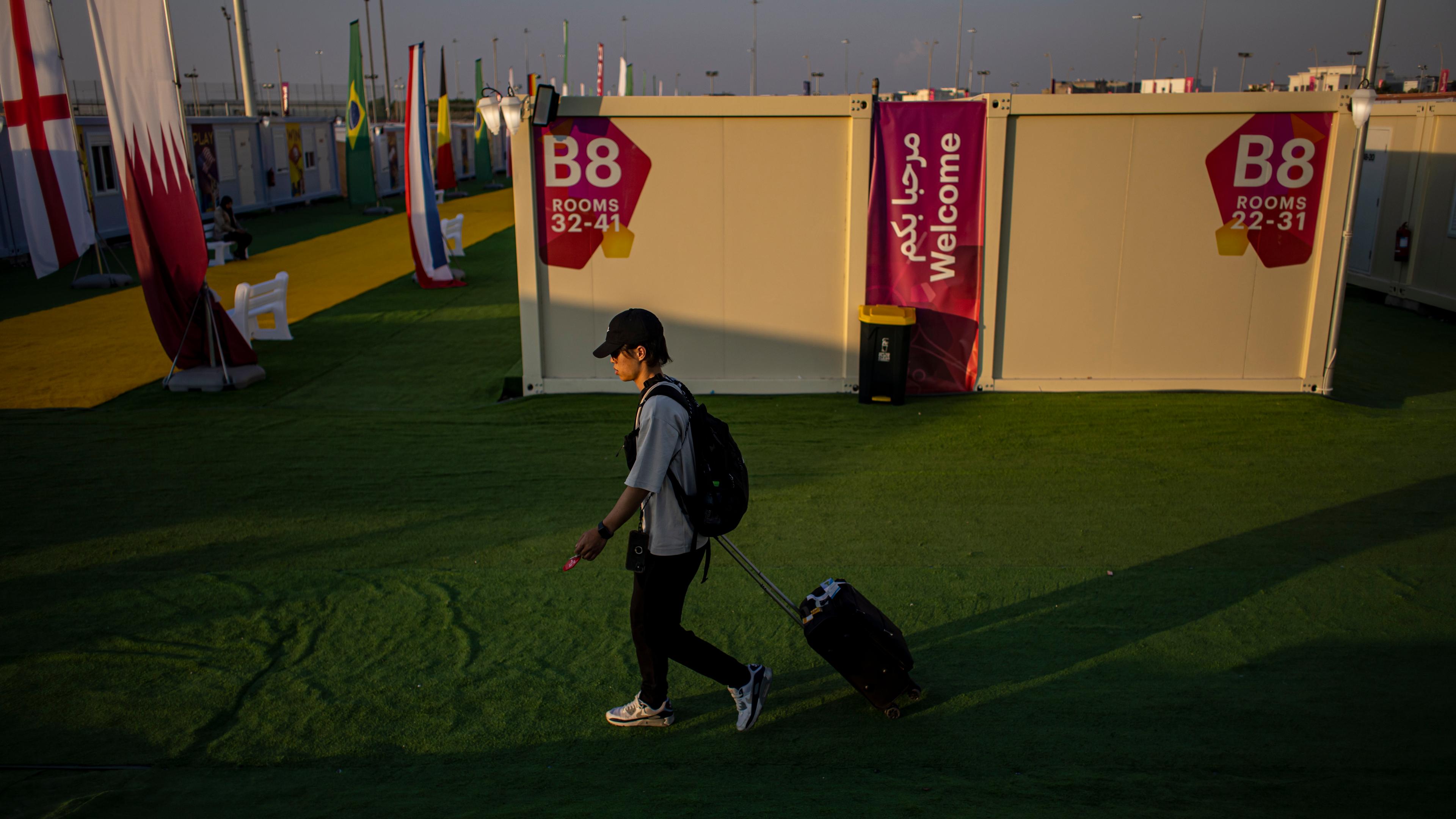 Katar, Doha: Ein Fußballfan ist im Fandorf mit einem Koffer unterwegs