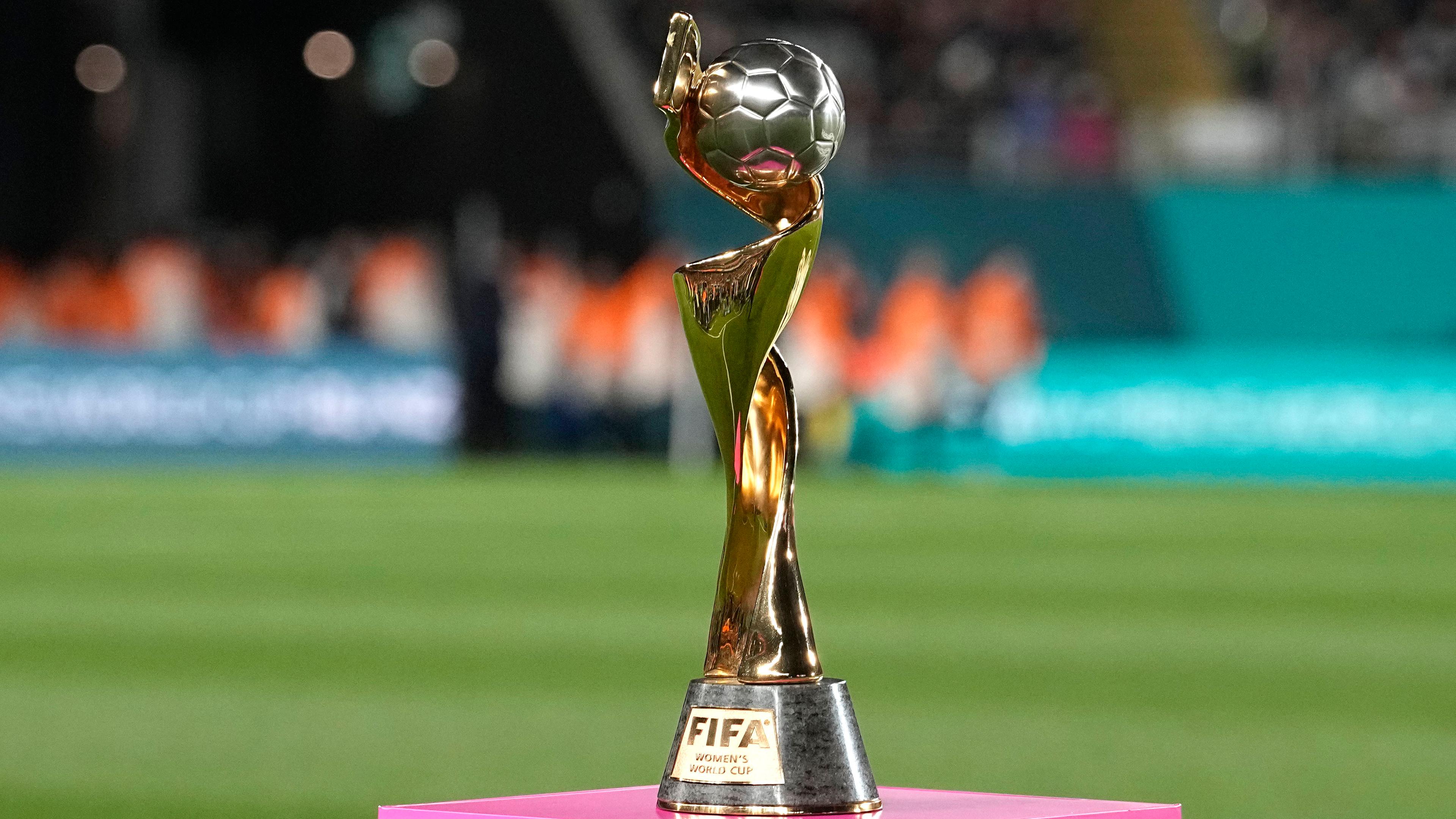 FIFA-Trophäe der Fußball-WM der Frauen wird auf einem pinken Sockel auf einem Fußballfeld präsentiert