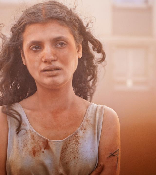 Man sieht eine Frau, die ein verschmutztes Oberteil trägt.