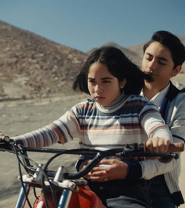 Ein Mädchen und ein Junge fahren auf einem Motorrad.