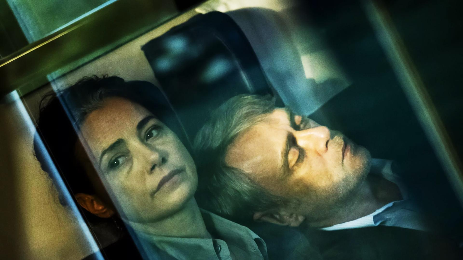 Ein Frau schaut aus einem Zugabteil nach draußen, an ihrer Schulter lehnt ein schlafender Mann.