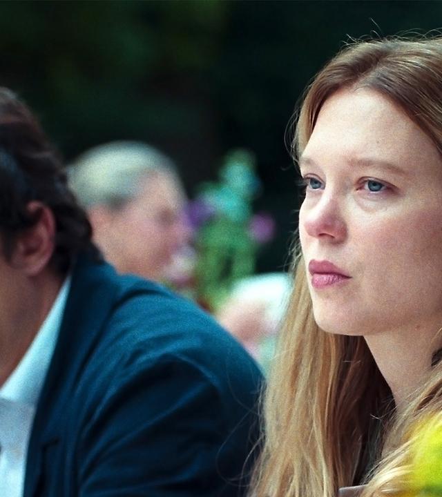 Eine Frau sitzt im Vordergrund und schaut missmutig nach links, neben ihr sitzt ein Mann und schaut nach unten.