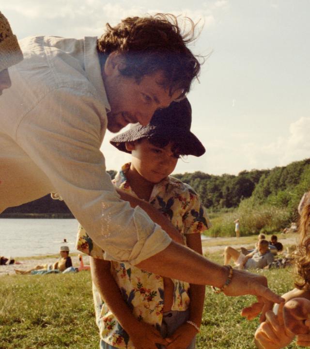 Man sieht eine Frau, einen Mann und zwei Kinder an einem See.