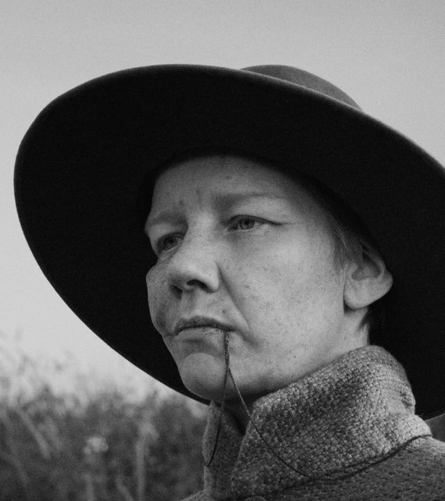 Auf einer Schwarz-Weiß-Fotografie sieht man eine Frau mit einem großen Hut.
