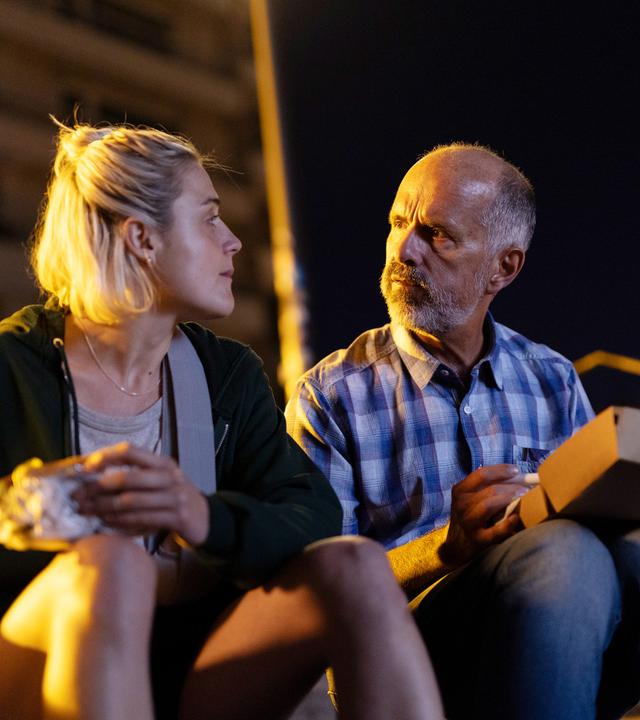 Eine blonde, junge Frau spricht mit einem älteren Mann.