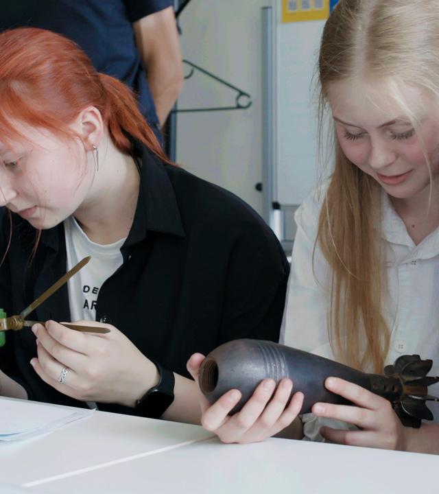 Mädchen sitzen an einem Tisch und halten Sprengsätze in den Händen.