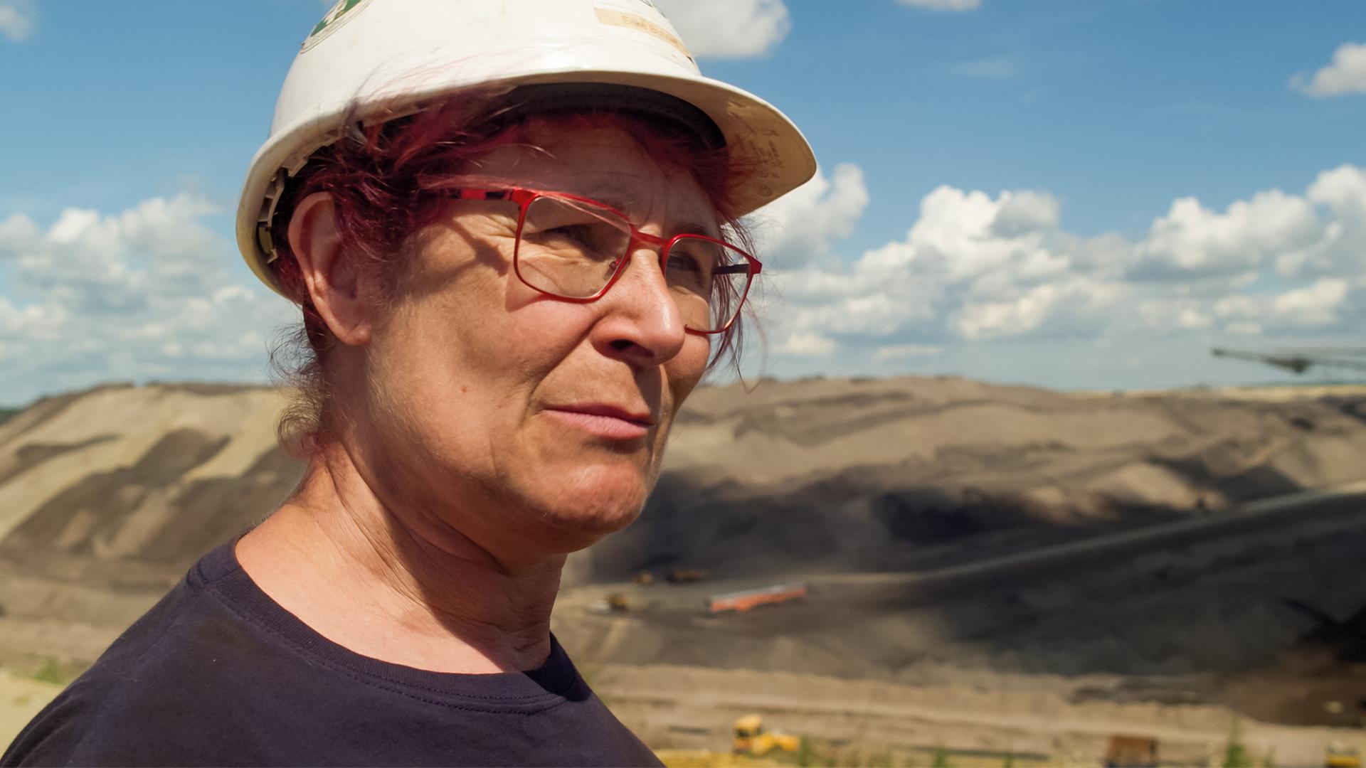 Eine Frau trägt einen Bauhelm in einem Tagebau.