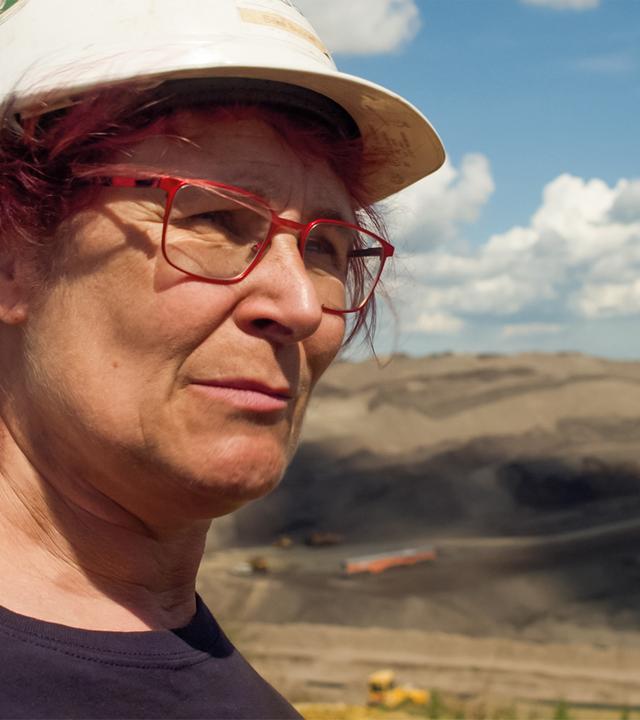 Eine Frau trägt einen Bauhelm in einem Tagebau.