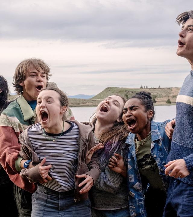 Eine Gruppe Teenager freut sich vor einem See.