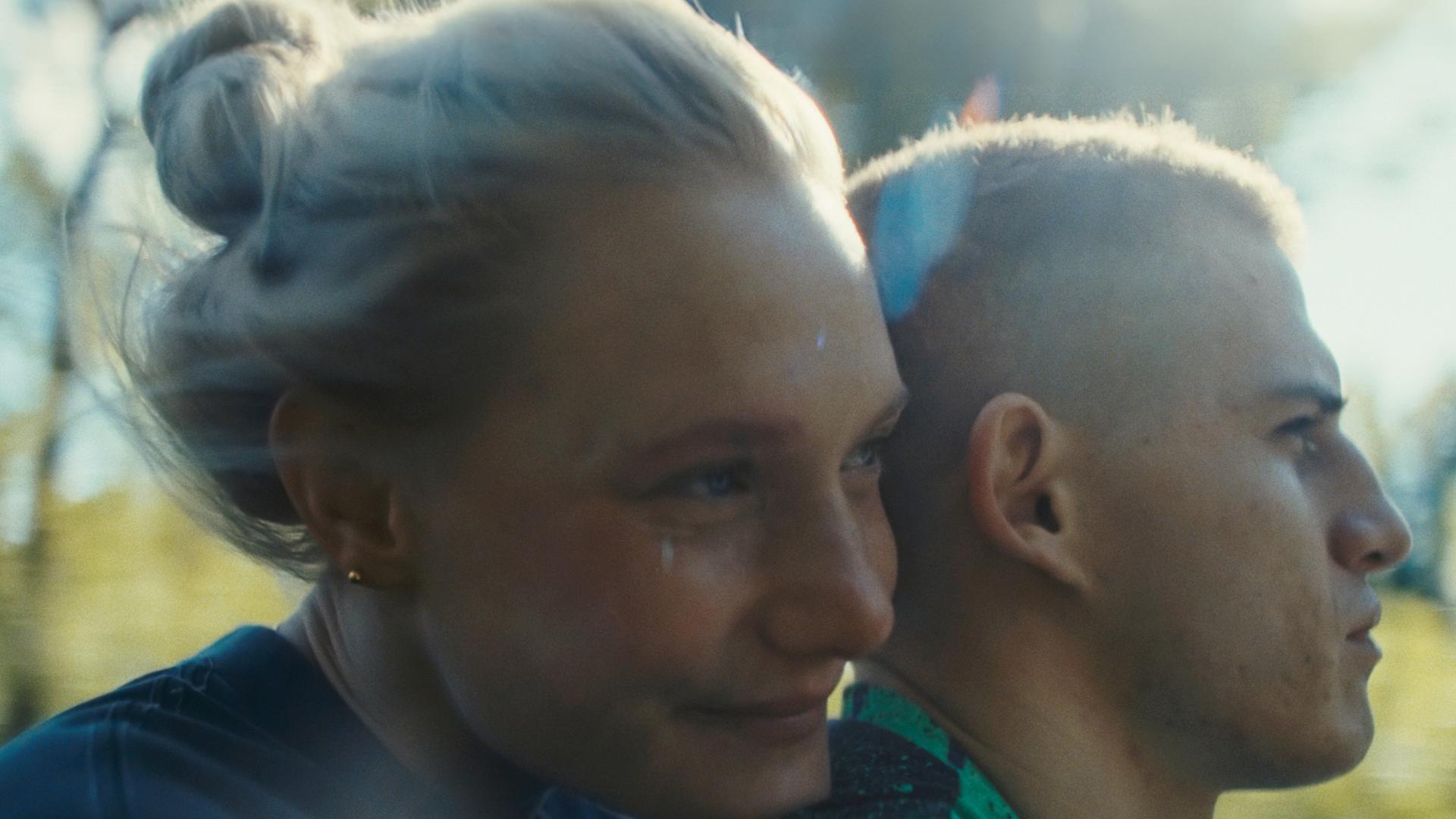 Eine junge Frau sitzt hinter einem jungen Mann auf einem Motorrad.