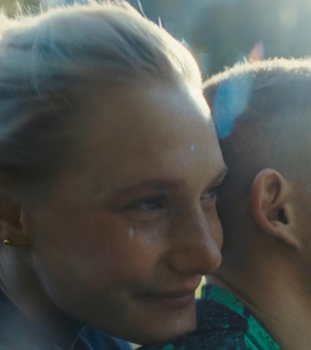 Eine junge Frau sitzt hinter einem jungen Mann auf einem Motorrad.