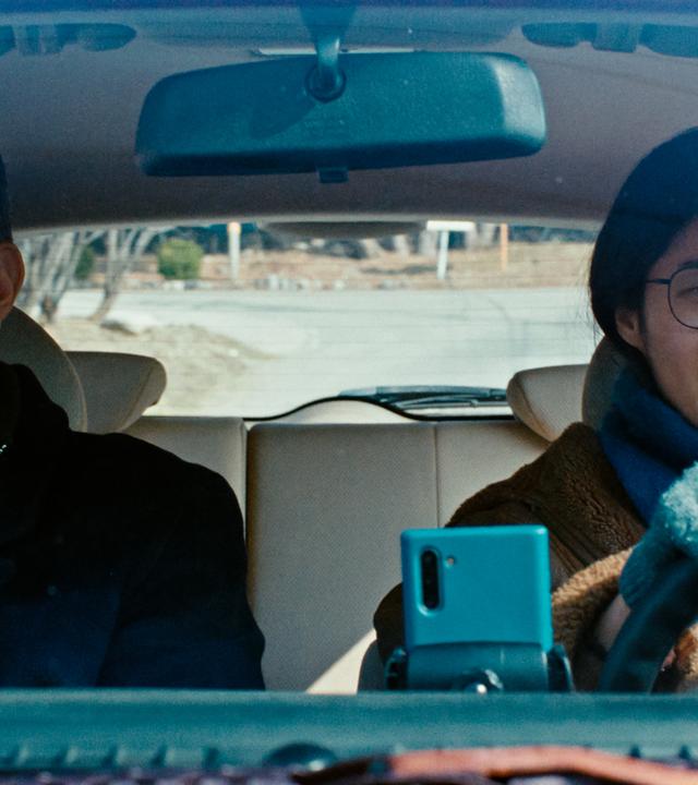 Eine Frau und ein Mann sitzen in einem fahrenden Auto.