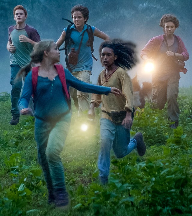 Die "Fünf Freunde" und ihre neue Freundin Joe (v.l.n.r.) rennen über eine Wiese: Joe (Davina Weber), Anne (Neele Marie Nickel), Julian (Quirin Oettl), Dick (Justus Schlingensiepen) und George (Valeria Eisenbart). Im Hintergrund ein Berg und davor Palmen.