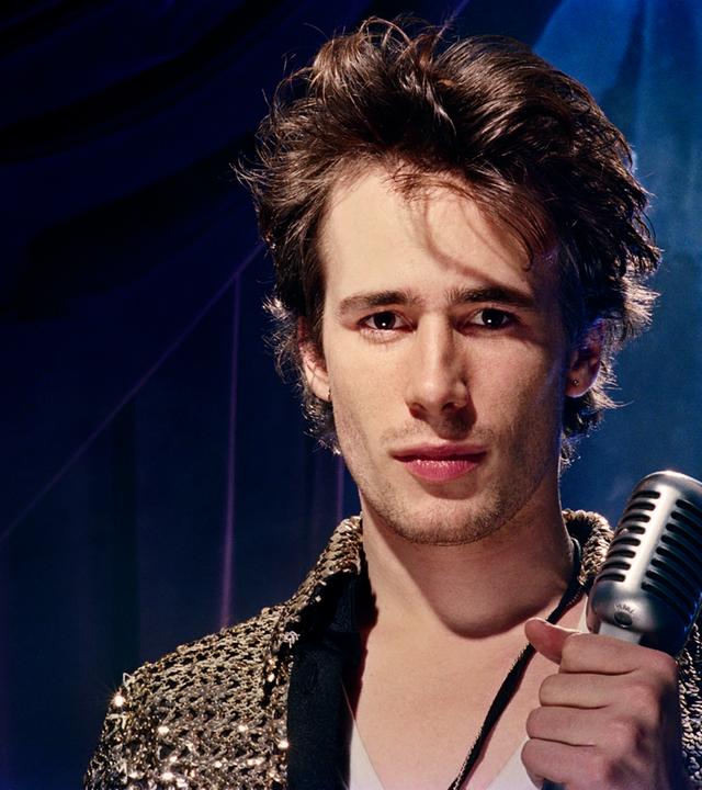 Mann hält Mikrofon in der Hand schaut in die Kamera