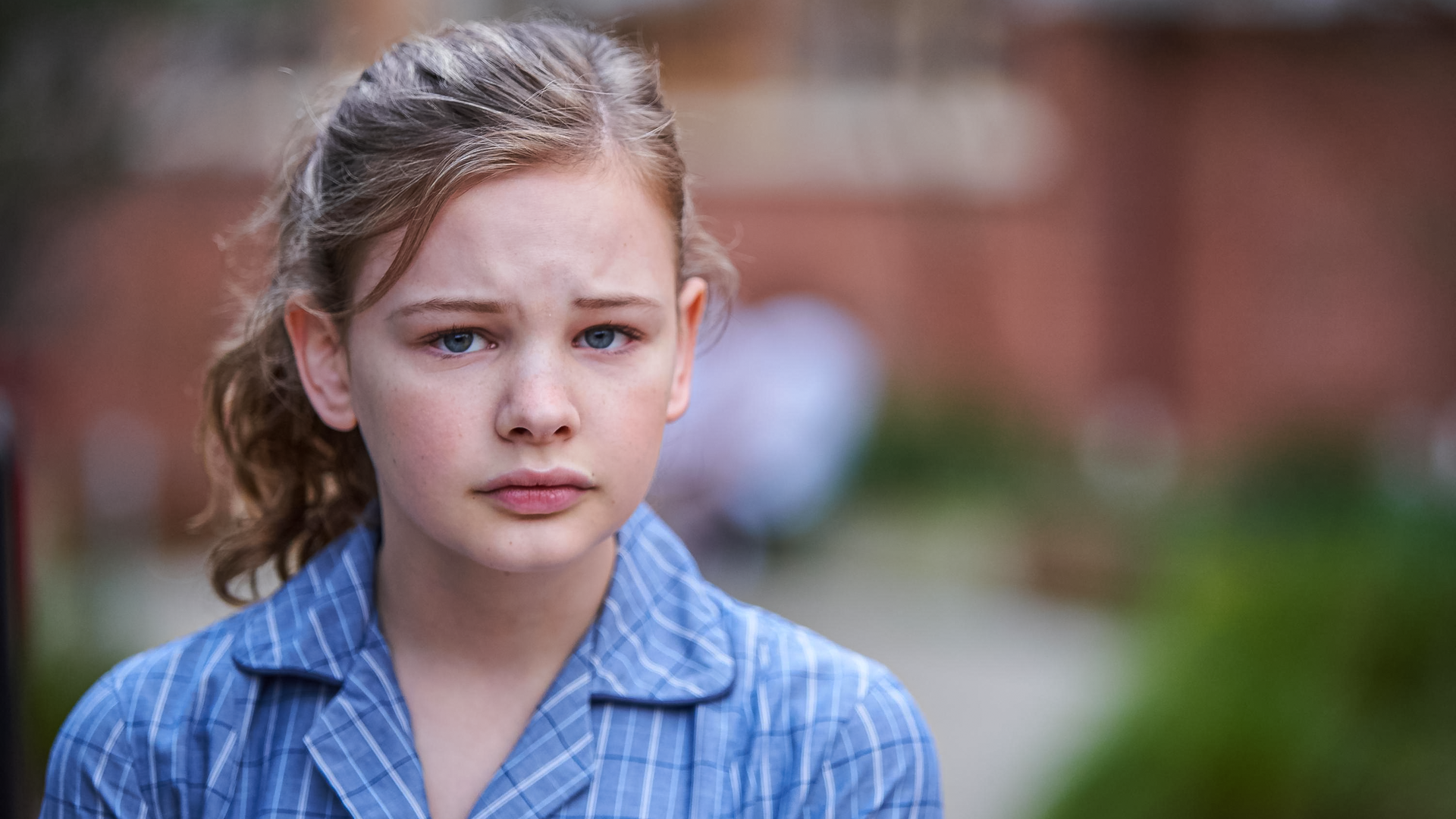 Das Transgendermädchen Hannah steht mit sorgenvollem Gesichtsausdruck vor dem Schulgebäude ihrer neuen Highschool.