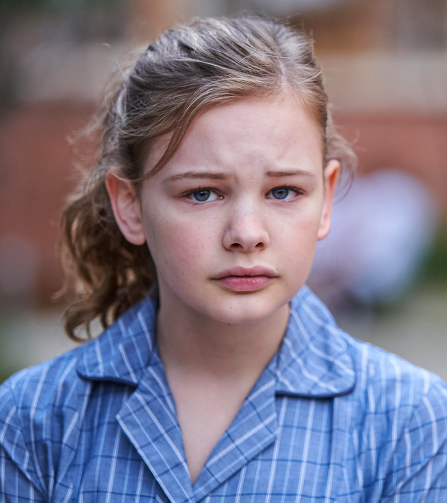 Das Transgendermädchen Hannah steht mit sorgenvollem Gesichtsausdruck vor dem Schulgebäude ihrer neuen Highschool.