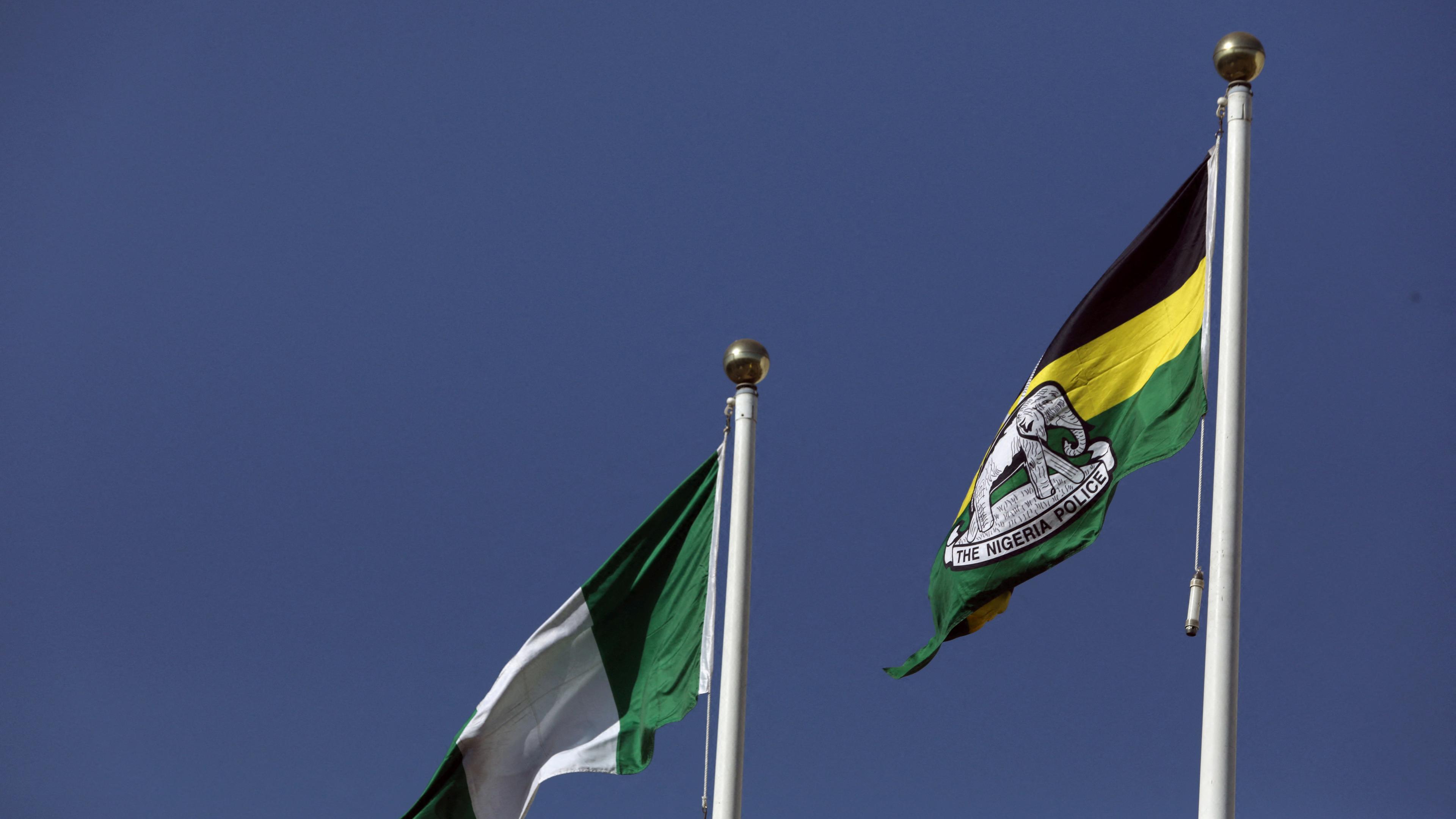 Zwei Flagge wehen im Wind. Links die Nationalflagge Nigerias, rechts die der nigerianischen Polizei.