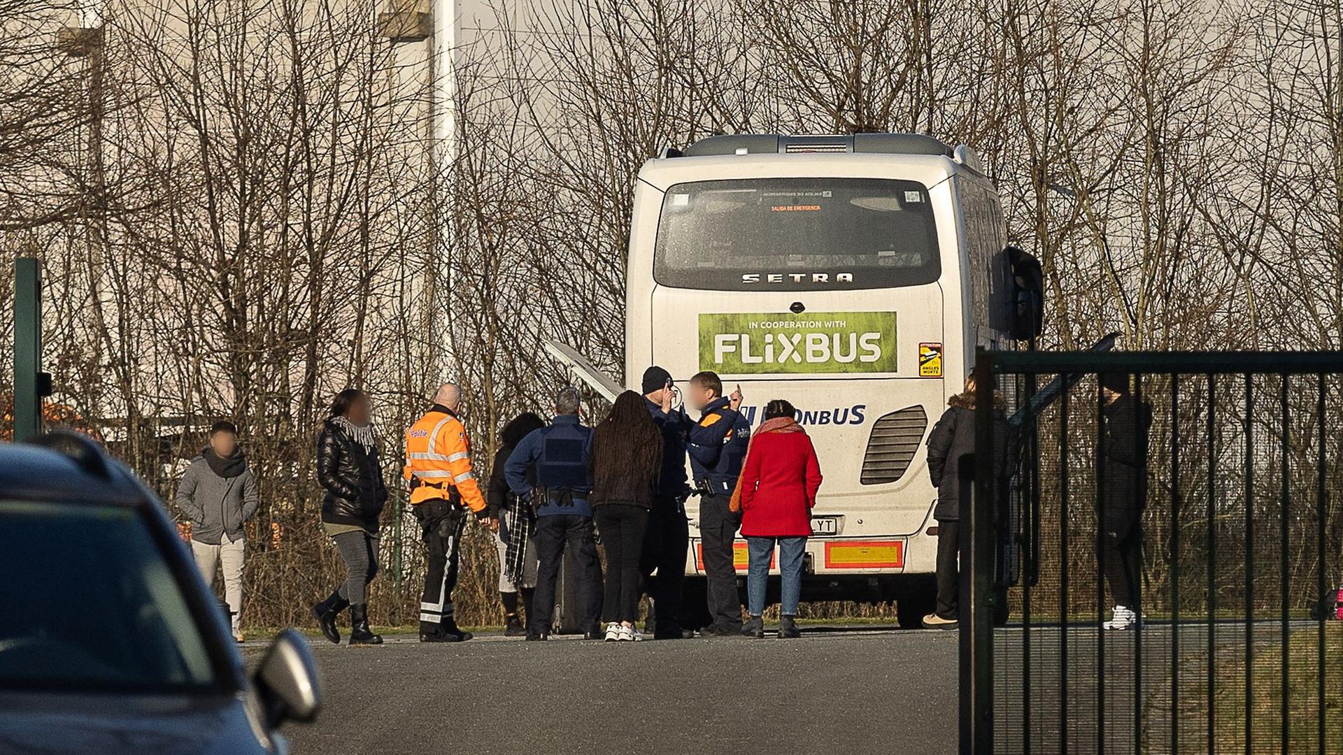 Belgische Polizisten und Fahrgäste stehen vor einem Überlandbus, der nach einem Bericht über ein Gespräch über einen möglichen Terroranschlag angehalten wurde am 11.01.2024.