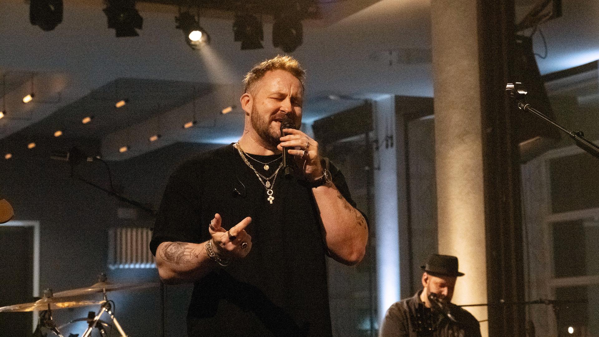 Florian Künstler singt in ein Mikrofon.