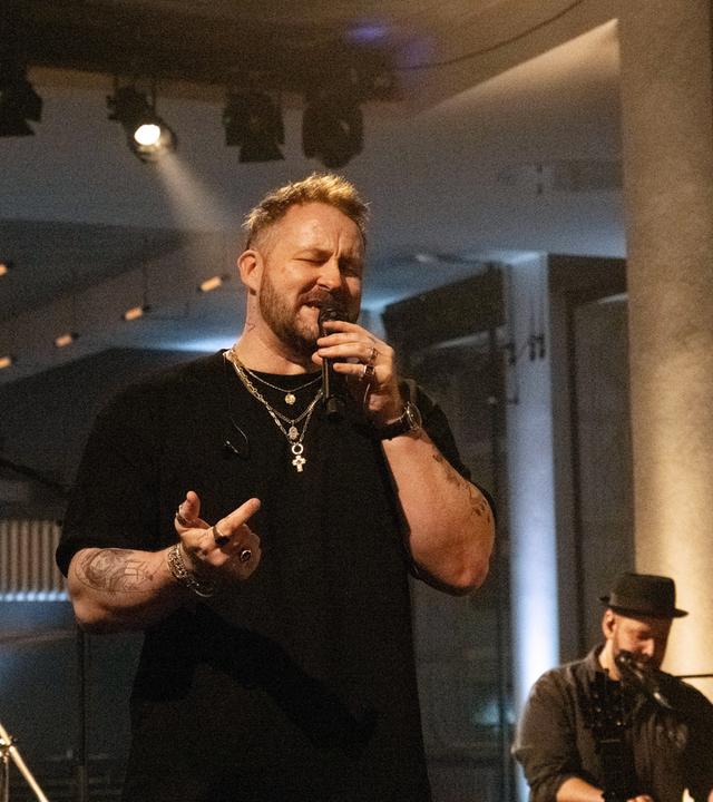 Florian Künstler singt in ein Mikrofon.