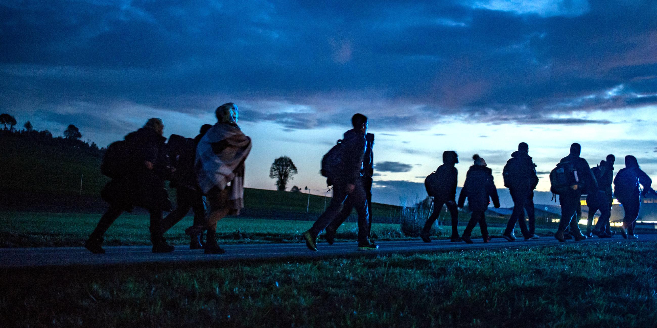 Archiv: Flüchtlinge gehen am 28.10.2015 hinter der deutsch-österreichischen Grenze in Wegscheid (Bayern) zu einer Notunterkunft