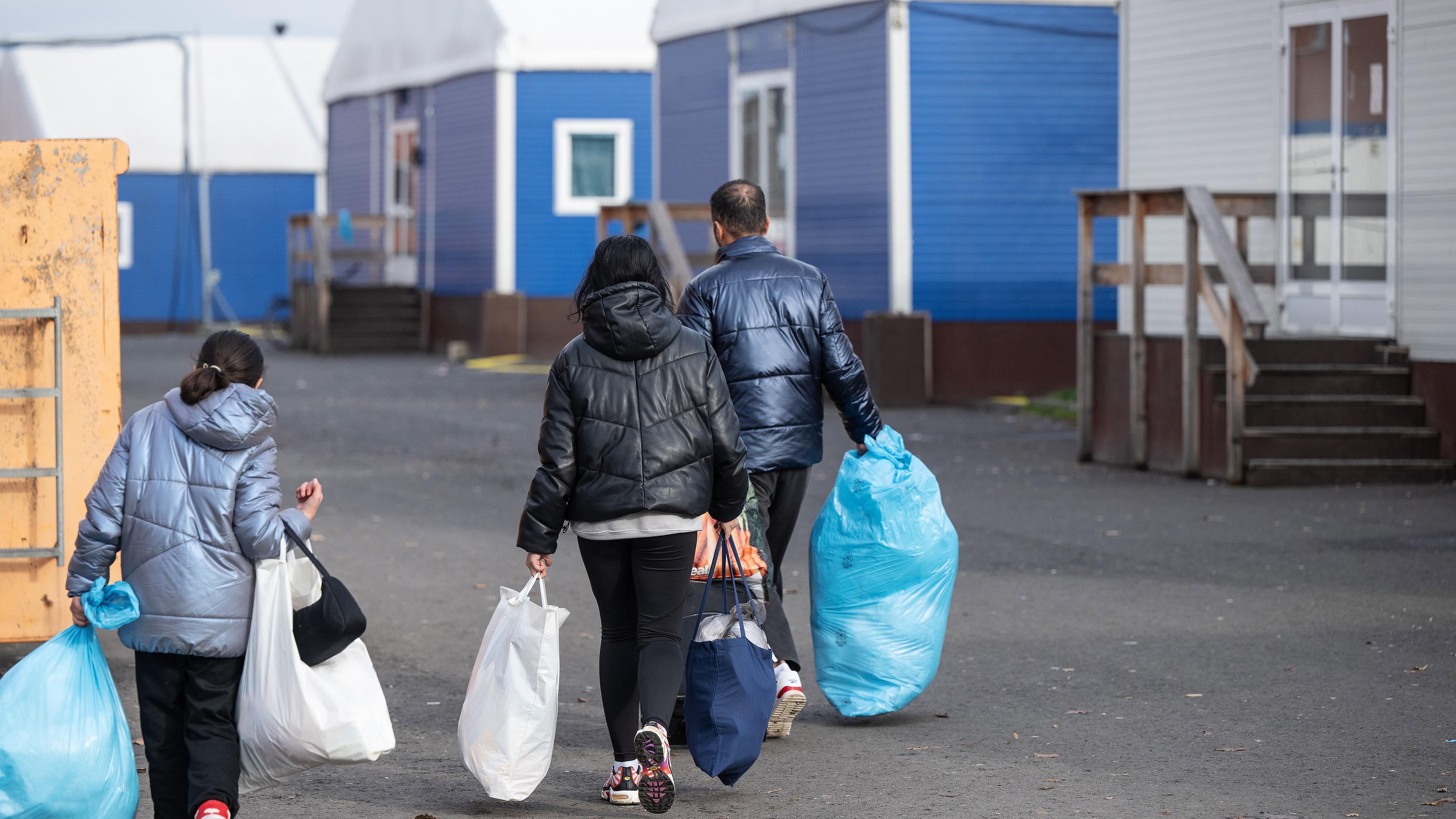 In Plastiksäcken tragen neu angekommene Flüchtlinge ihre persönlichen Habseligkeiten zu ihrer Unterkunft in der Erstaufnahmeeinrichtung (HEAE) in Gießen, aufgenommen am 22.11.2023