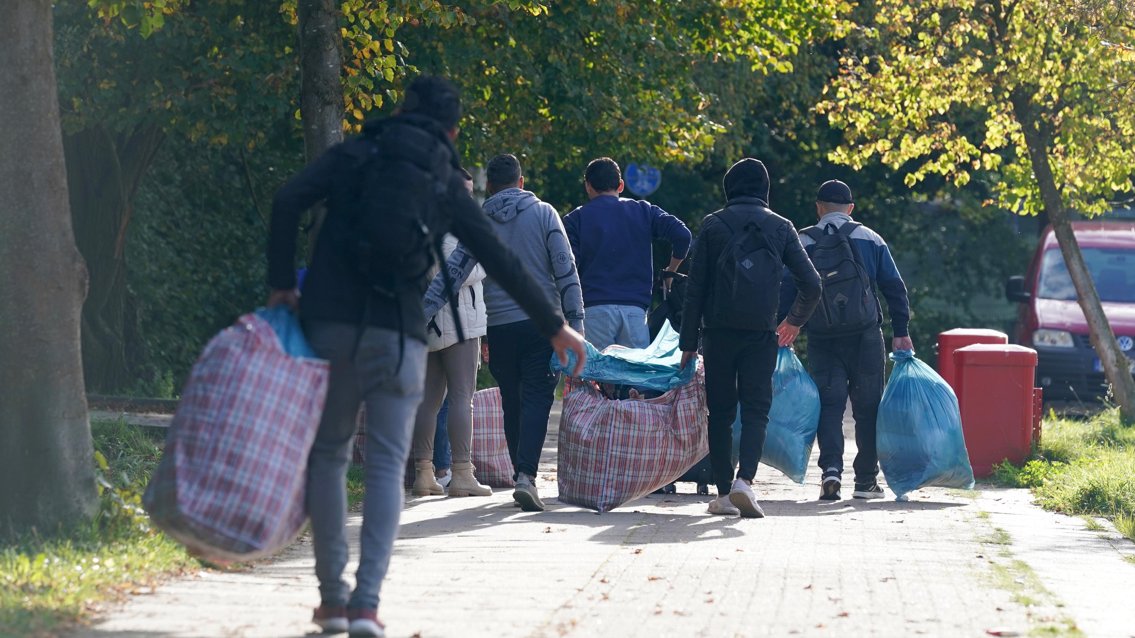 Flüchtlinge aus Syrien gehen mit ihrem Gepäck zu der Flüchtlingsunterkunft im Alma-Ohlmann-Weg im Stadtteil Lokstedt, aufgenommen am 17.10.2023
