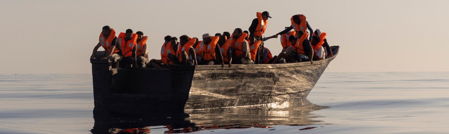 Ein Holzboot voller Menschen auf dem Mittelmeer