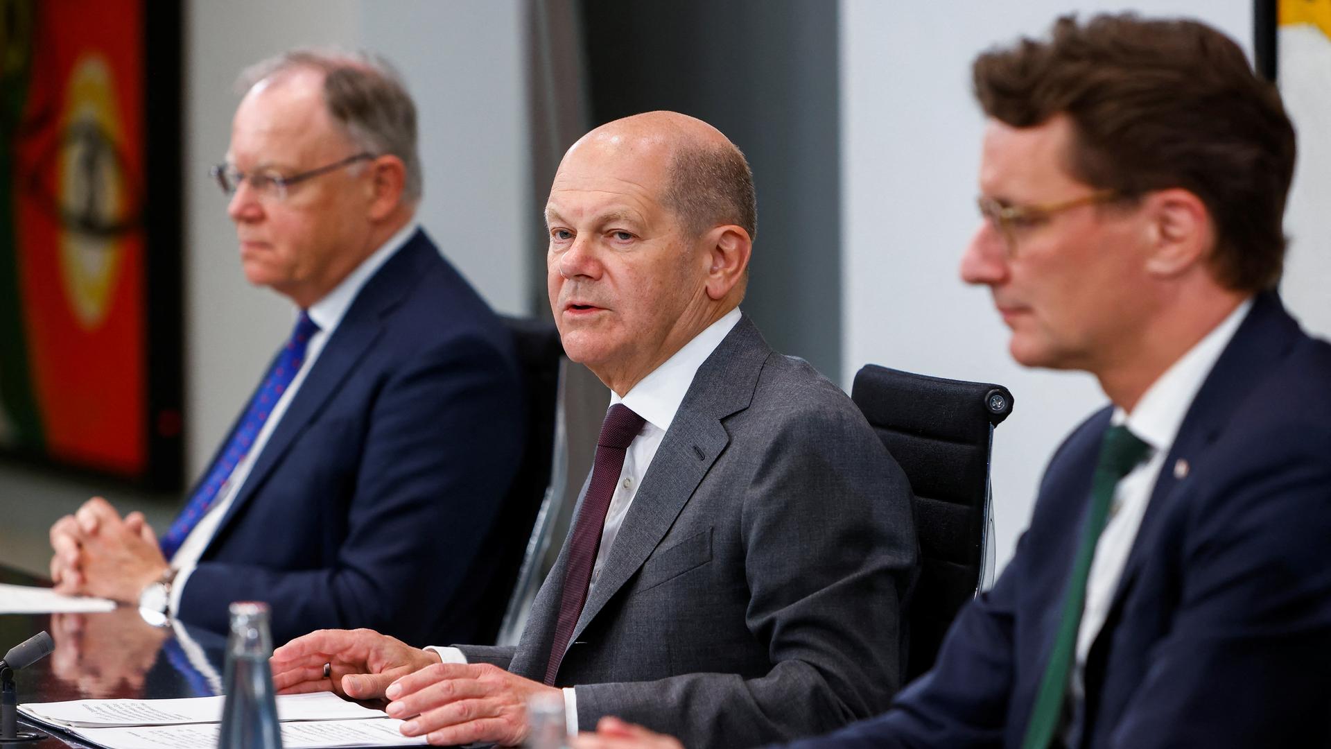 Zu sehen ist Bundeskanzler Olaf Scholz, flankiert von Stephan Weil, Vorsitzender der Ministerpräsidentenkonferenz, sowie Henrik Wüst, Ministerpräsident von NRW.