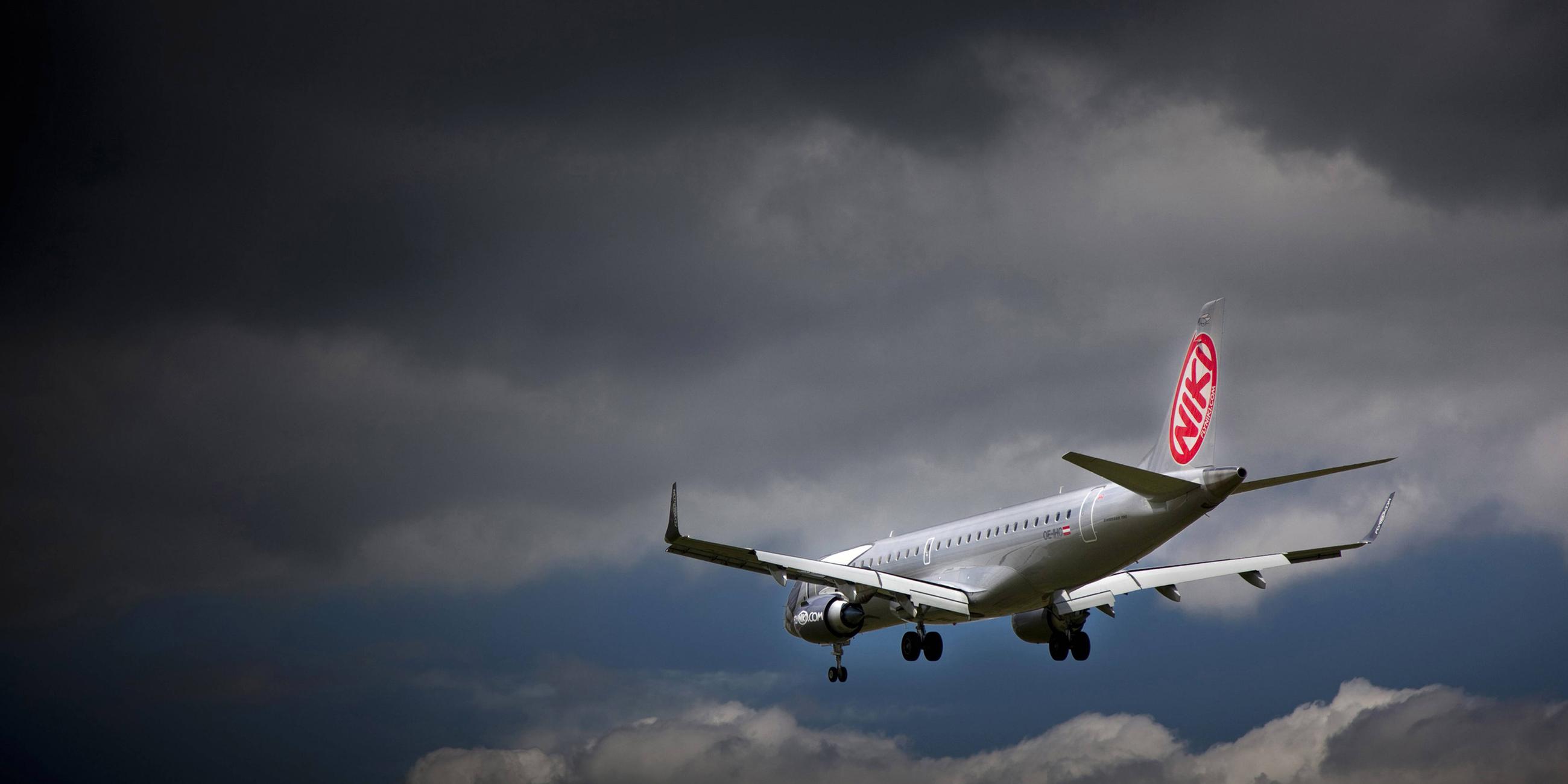 Maschine der Fluggesellschaft Niki fliegt unter dunklen Wolken 