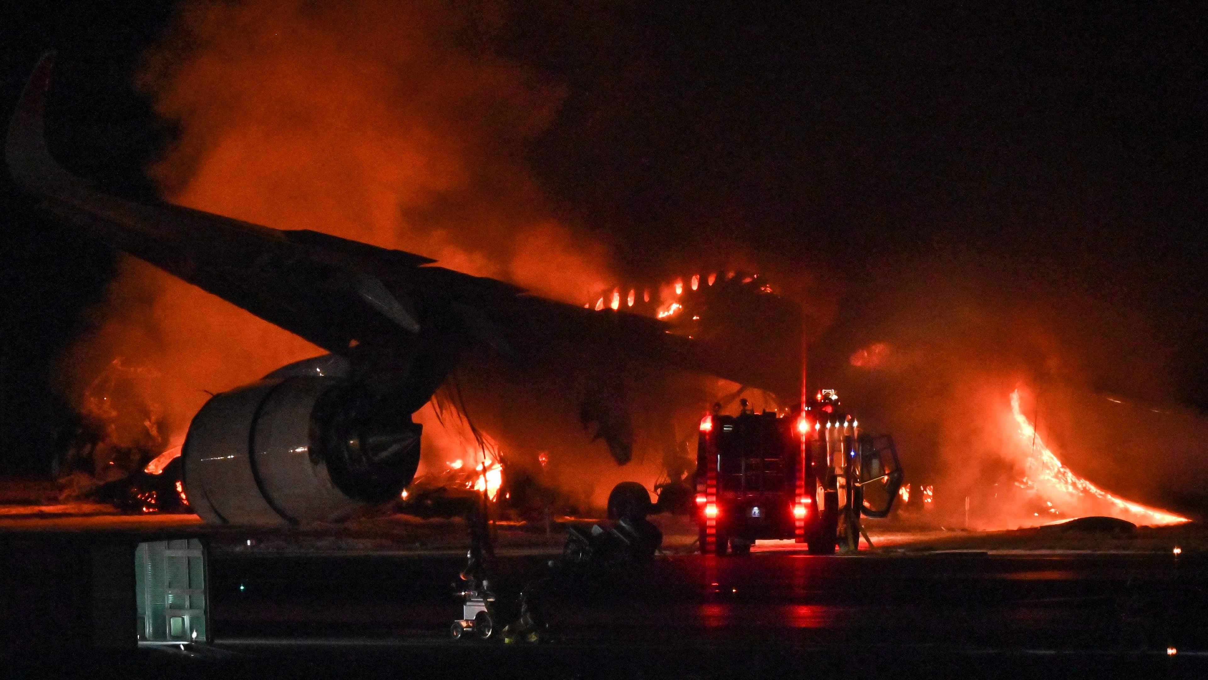 Ein Passagierflugzeug steht auf dem Tokioter Flughafen in Flammen.