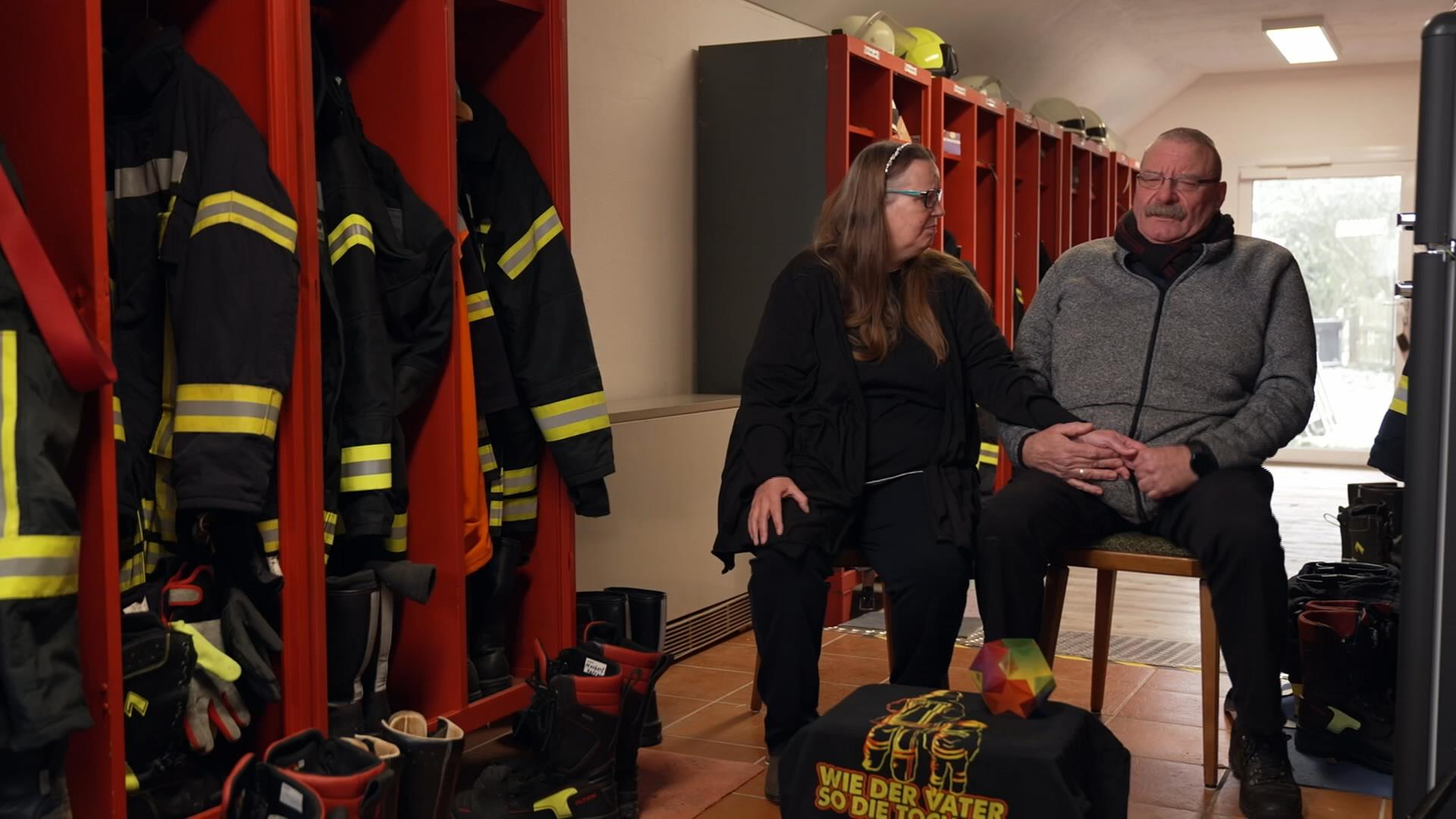 Eheleute Kraatz sitzt neben Spinten der Feuerwehr