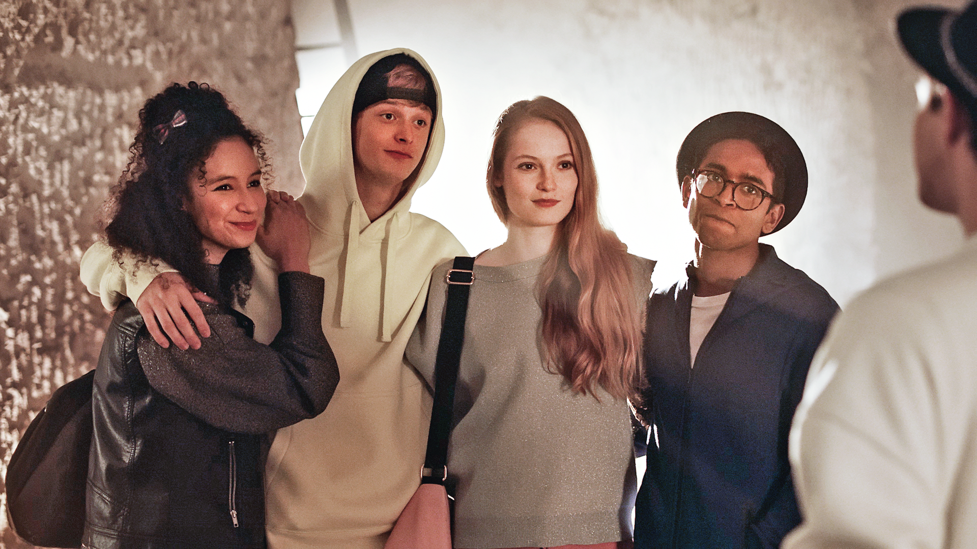 Eine kleine Gruppe Ballettschüler steht in einer Reihe und sieht provokant zu einem jungen Mann herüber, der rechts im Bild steht.