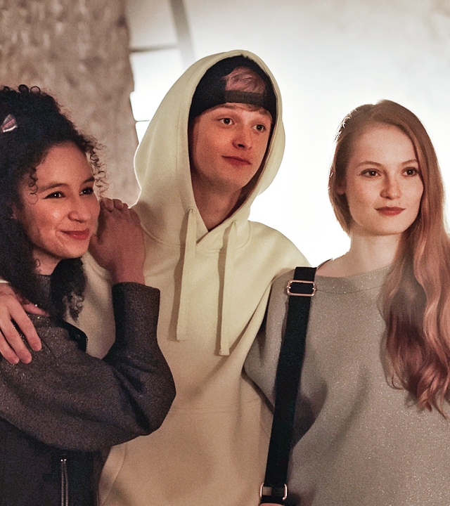 Eine kleine Gruppe Ballettschüler steht in einer Reihe und sieht provokant zu einem jungen Mann herüber, der rechts im Bild steht.