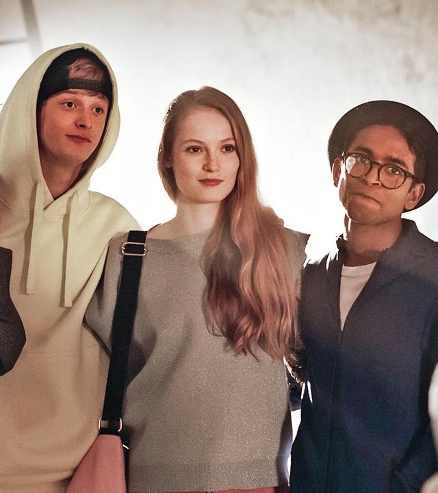 Eine kleine Gruppe Ballettschüler steht in einer Reihe und sieht provokant zu einem jungen Mann herüber, der rechts im Bild steht.