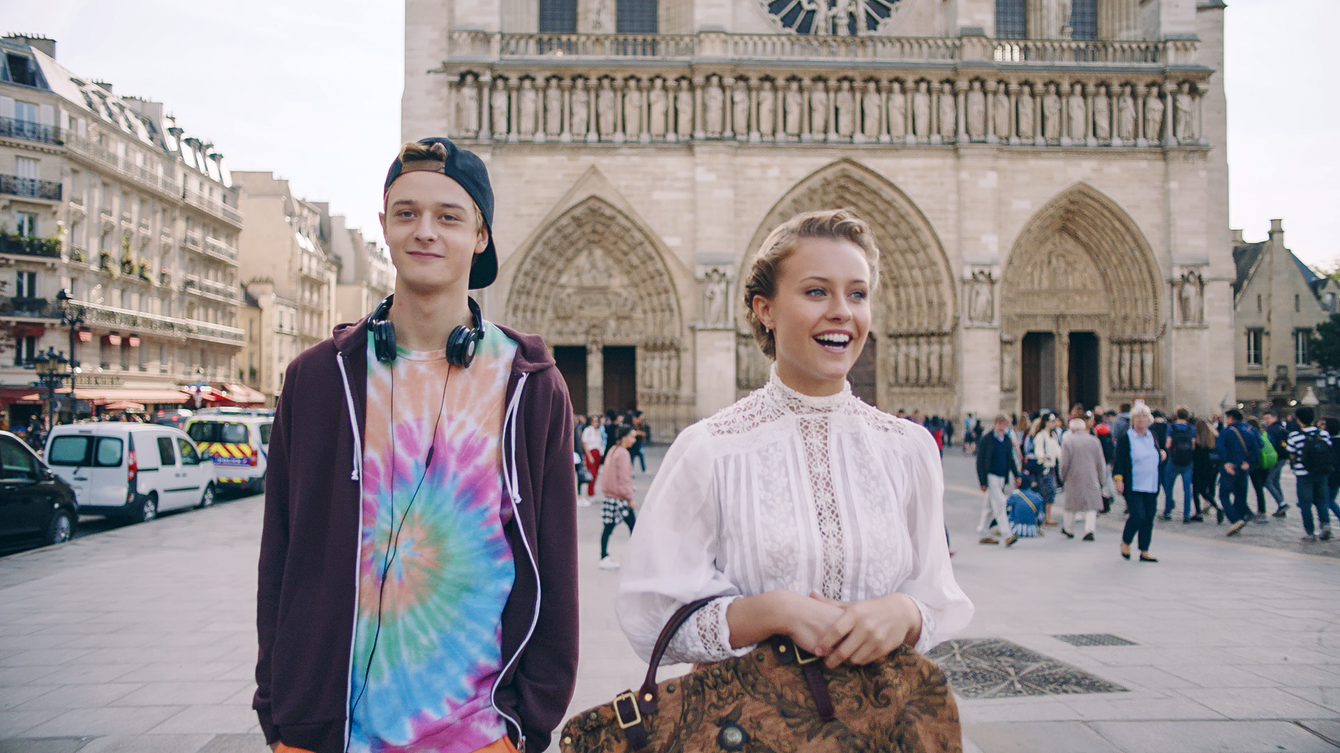 Lena läuft mit Jeff durch die Stadt. Beide haben ein Lächeln auf den Lippen. Im Hintergrund ist die Notre Dame zu sehen.