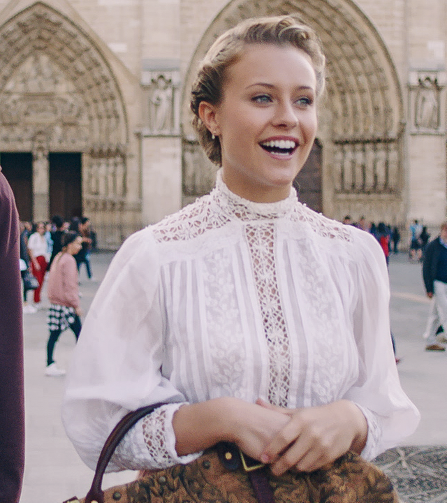 Lena läuft mit Jeff durch die Stadt. Beide haben ein Lächeln auf den Lippen. Im Hintergrund ist die Notre Dame zu sehen.