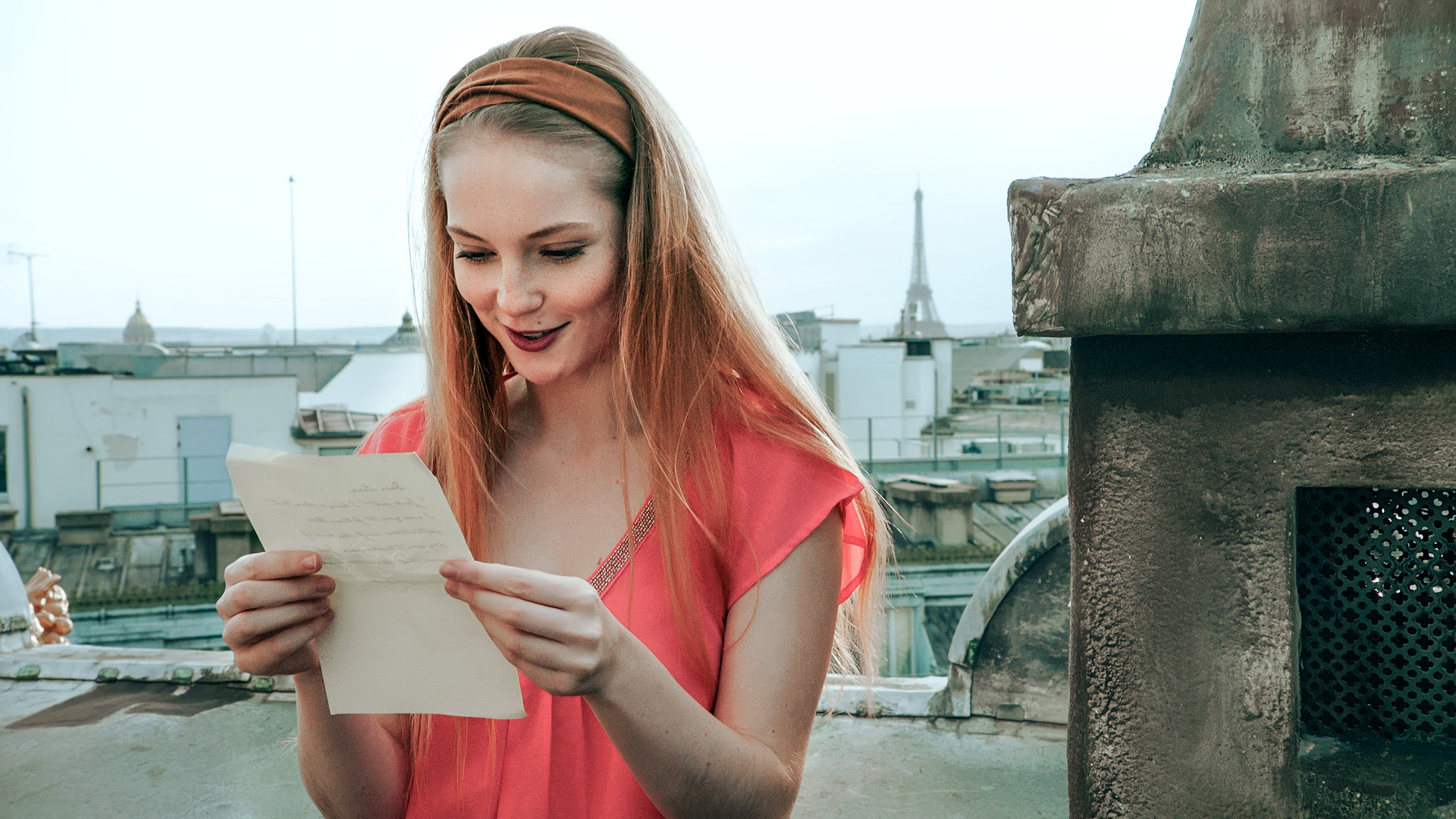 Thea hält einen Zettel in ihrer Hand. Sie liest, was darauf steht und lächelt.