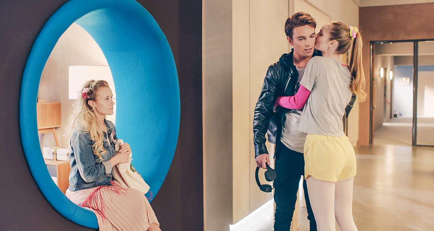 Max wird von Thea auf die Wange geküsst. Lena sitzt links daneben.