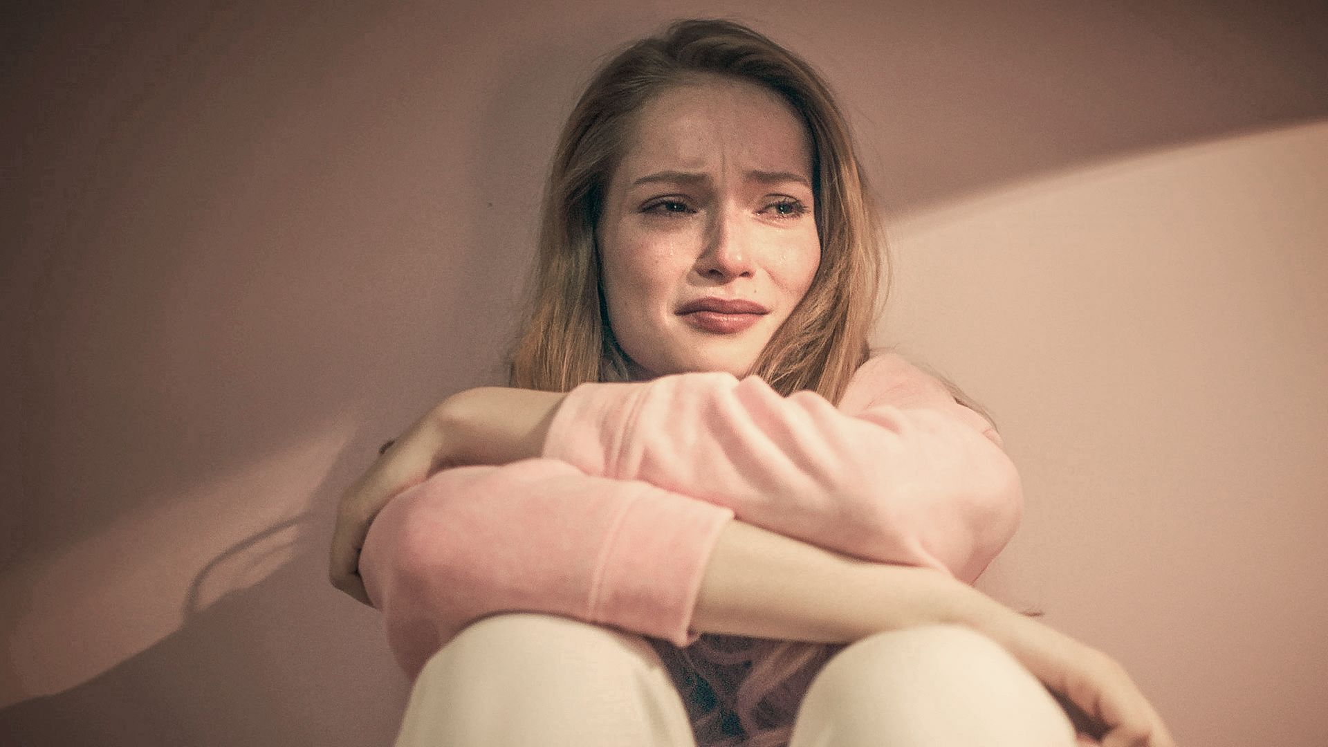 Thea sitzt weinend auf dem Boden und hat die Arme vor sich verschränkt.